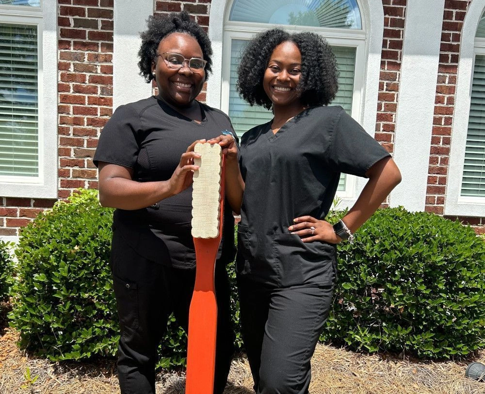 students posing with life size toothbrush outside of the facility